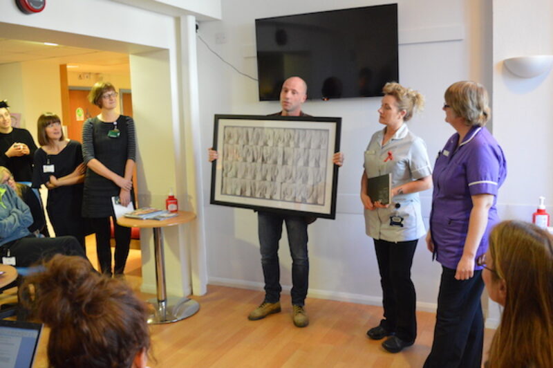 Jamie McCartney presents a signed Great Wall of Vagina photograph at the Brighton SHAC sexual health clinic